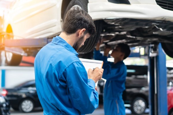 car tech looking over a vehicle on a hoist